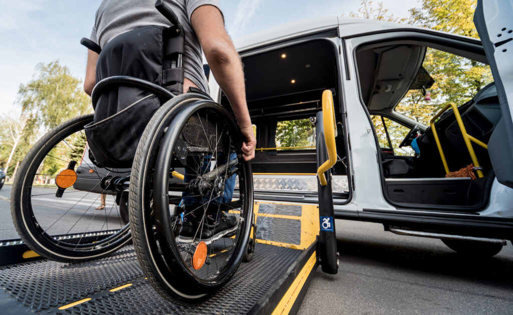 A person in a wheelchair accessing a Spokane Transit van equipped with a wheelchair ramp, focusing on the wheelchair's wheels as they roll onto the ramp.