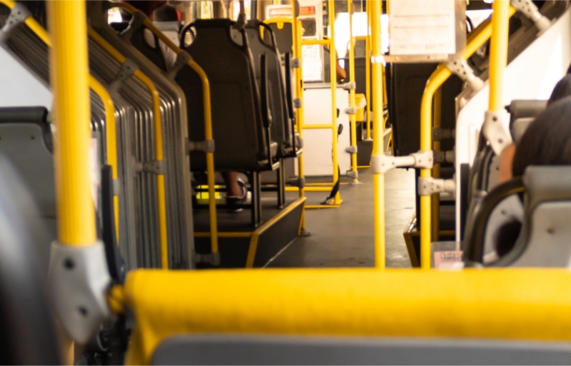 Inside of a Spokane Transit city bus showing yellow handrails and scattered seating with passengers, focusing towards the rear section with blurred details.