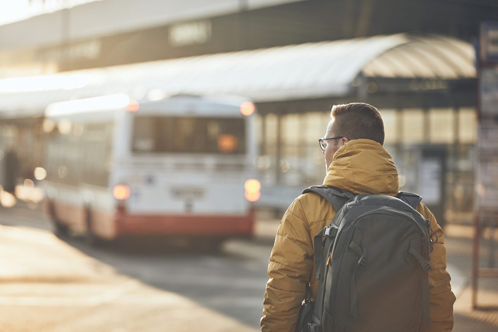 An image of a man with his back to the camera walking towards his bus as the sun rises.