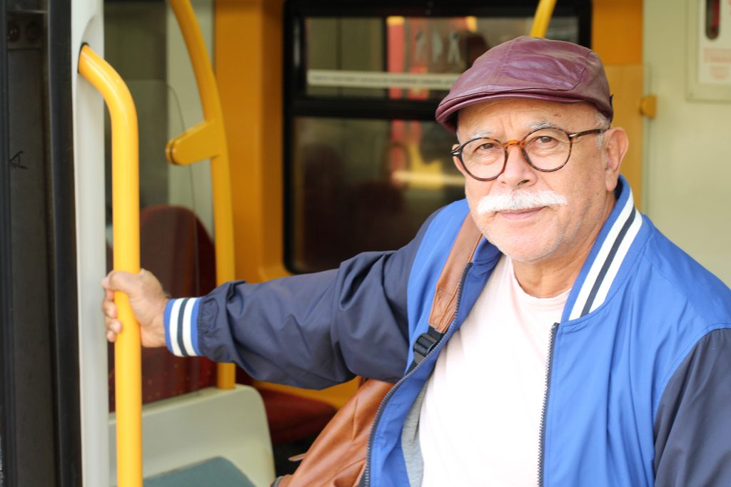 An image of an elderly man riding on a bus.