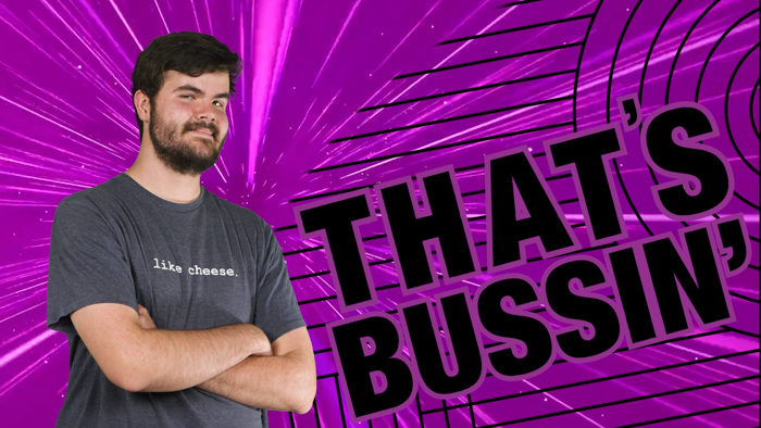 A man with short dark hair and a beard stands with his arms crossed, wearing a gray t-shirt that says "I like cheese." Behind him is a vibrant purple background with black starbursts and lines. A large, bold text on the right reads, "THAT'S BUSSIN’.
