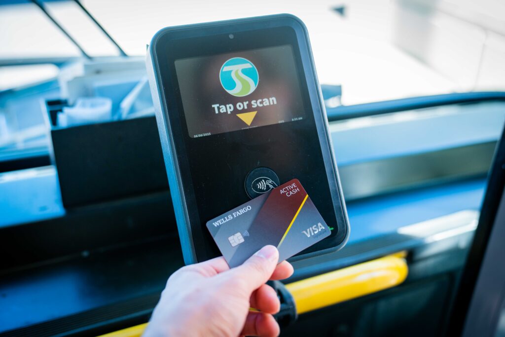 A person paying their bus fare with a credit card by tapping it on a card reader.