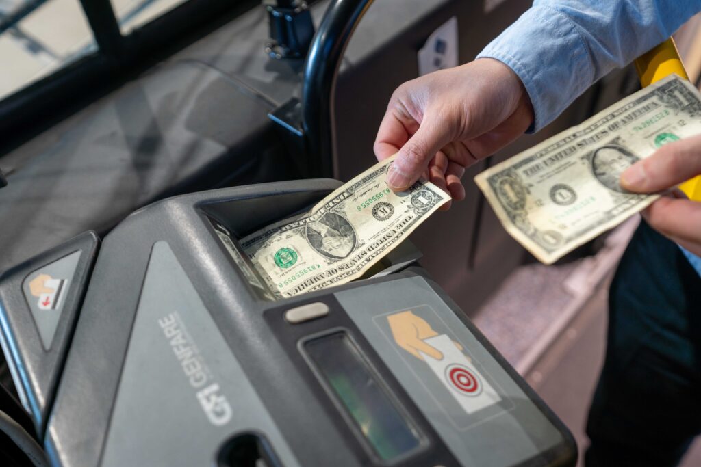 A person paying for a bus fare with cash, he is putting a dollar bill into a machine.