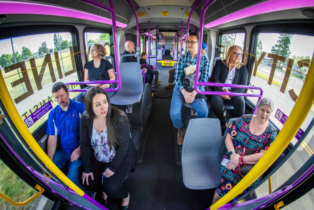 Several passengers are seated on a bus, some looking out the windows, while others are engaged in conversation.