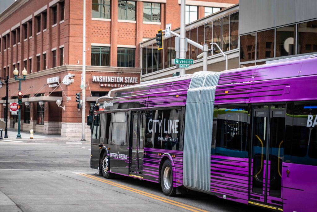 A purple city bus passes through an intersection near the Washington State University athletic center.