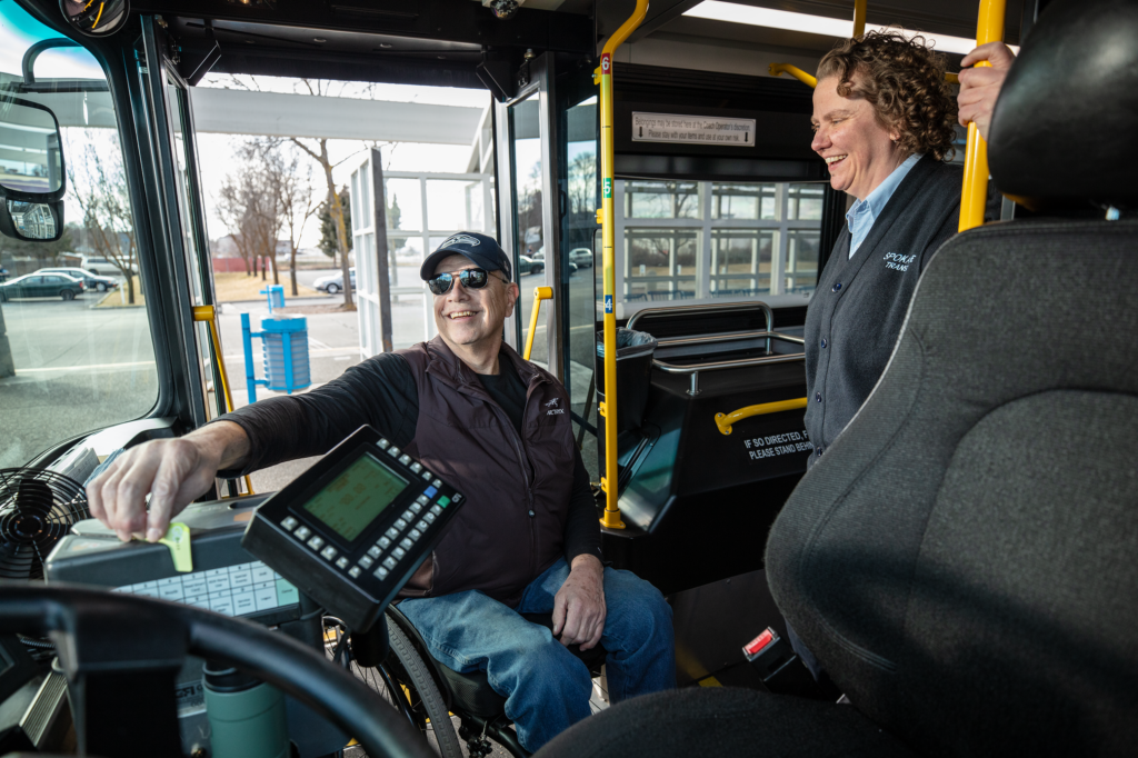 A business person amiably chatting with an STA bus driver while the bus is parked.