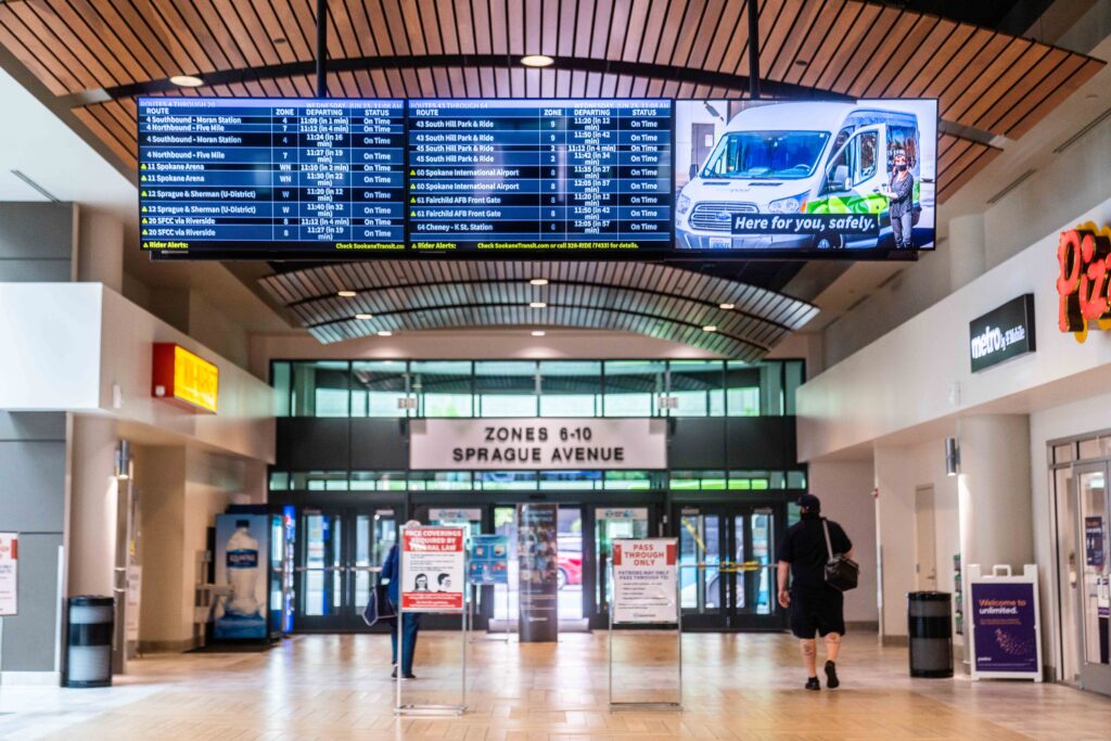 Interior view of a transit center showcasing STA's recent projects and plans, featuring digital bus schedules and clear signs for different zones and shops.