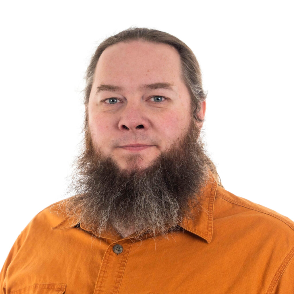 Man with a long beard and long hair wearing an orange shirt against a white background.