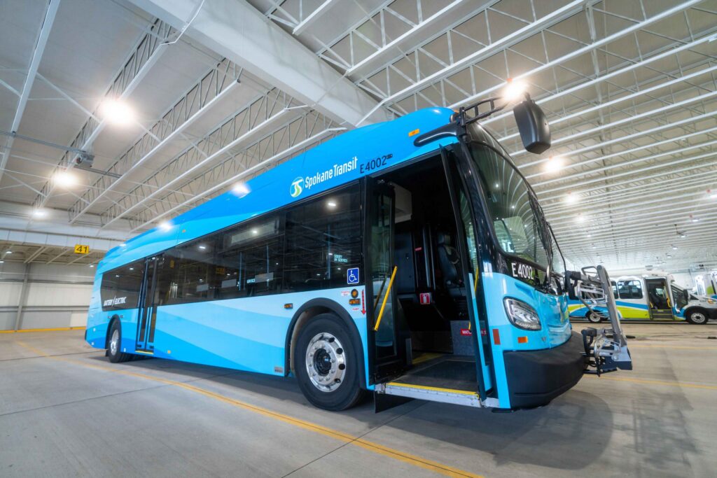 Electric bus parked in a well-lit garage, featuring a blue and white design with numbered markings.