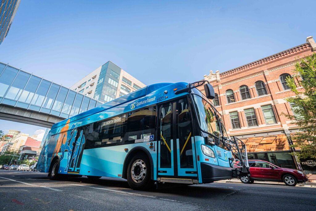 Blue STA bus with vibrant design on a street near modern and brick buildings under a clear sky.