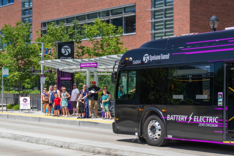 Group waiting at Spokane & S. Sherman bus stop as STA City Line bus arrives.
