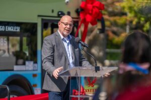 City of Cheney Mayor and STA Board Member Chris Grover speaks at the podium in front of the double-decker bus.