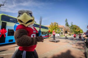 Swoop doing Swoop things with Karl Otterstrom in the background speaking to the crowd.
