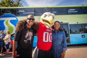 City of Spokane Council President and STA Board Member Besty Wilkerson and a family member poses with Swoop in front of the double-decker bus.