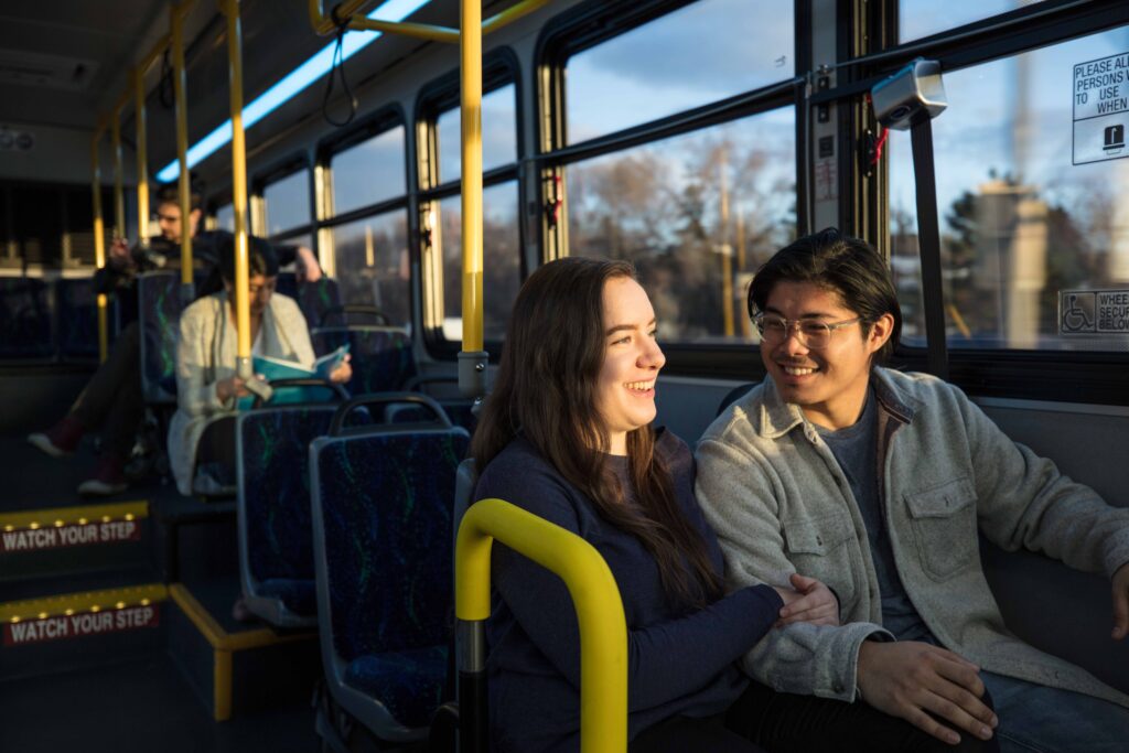 A couple smiles together on a bus.