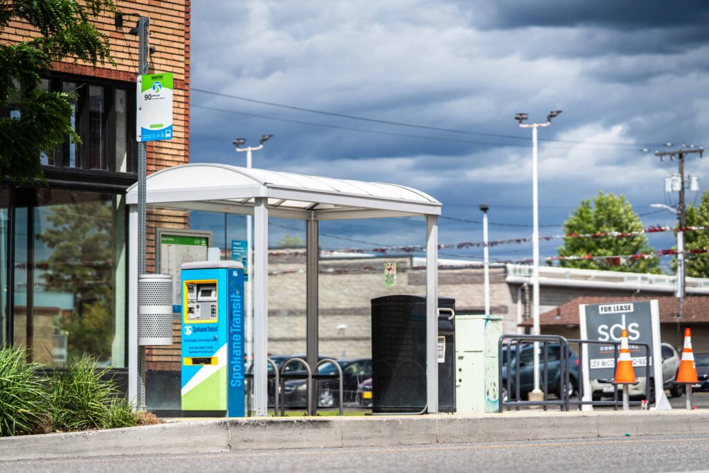 Bus stop shelter with a ticket machine on a city street.