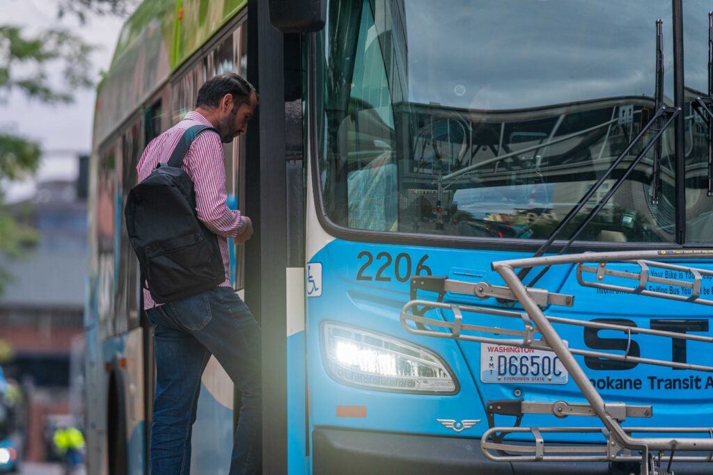 Man with backpack boards blue Spokane Transit bus.