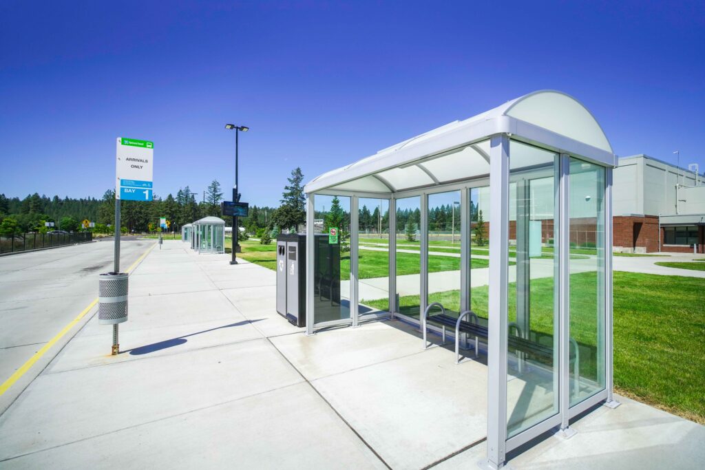 Modern glass bus shelter at an empty transit station.