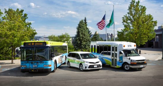 an STA Bus, Vanpool Van, and Paratransit Van in front of the flags of the United States and Washington State.