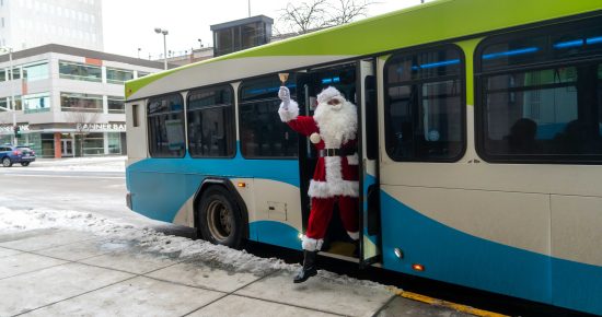 Santa Claus stepping off an STA bus, ringing a bell in downtown Spokane.