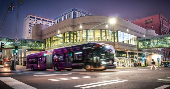 An STA bus drives past the STA Plaza at dusk.